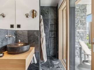 Experience luxury in this modern bathroom featuring a striking stone vessel sink atop a warm wooden vanity.