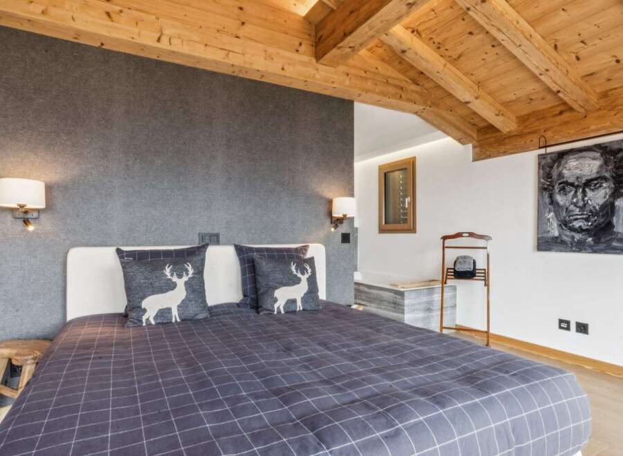 Experience rustic charm in this cozy bedroom featuring a comfortable bed adorned with decorative pillows showcasing a woodland motif.