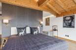 Experience rustic charm in this cozy bedroom featuring a comfortable bed adorned with decorative pillows showcasing a woodland motif.