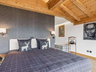Experience rustic charm in this cozy bedroom featuring a comfortable bed adorned with decorative pillows showcasing a woodland motif.