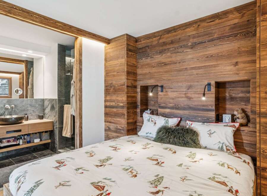 Experience rustic charm in this cozy bedroom featuring a unique ski-themed duvet cover and warm wood paneling.