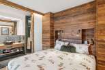 Experience rustic charm in this cozy bedroom featuring a unique ski-themed duvet cover and warm wood paneling.