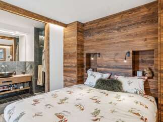 Experience rustic charm in this cozy bedroom featuring a unique ski-themed duvet cover and warm wood paneling.