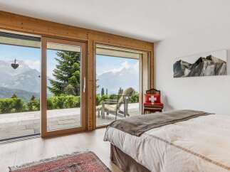 Experience breathtaking mountain views from this serene bedroom, featuring expansive sliding glass doors that open to a private balcony.