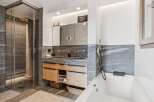 Experience modern luxury in this stunning bathroom featuring a spacious walk-in shower with sleek stone tilework and a rainfall showerhead.