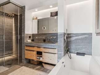 Experience modern luxury in this stunning bathroom featuring a spacious walk-in shower with sleek stone tilework and a rainfall showerhead.