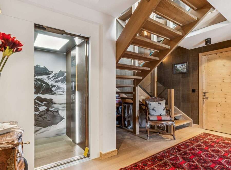 Experience luxury mountain living with this stunning property featuring a modern glass elevator and a beautiful wooden staircase.