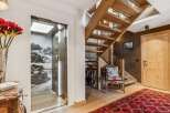 Experience luxury mountain living with this stunning property featuring a modern glass elevator and a beautiful wooden staircase.