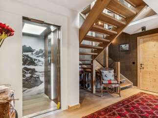 Experience luxury mountain living with this stunning property featuring a modern glass elevator and a beautiful wooden staircase.