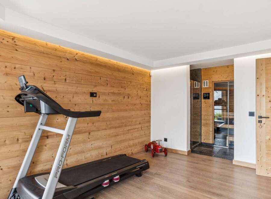 This modern gym area features a Pro-Form treadmill set against a warm, wood-paneled wall with ambient lighting.