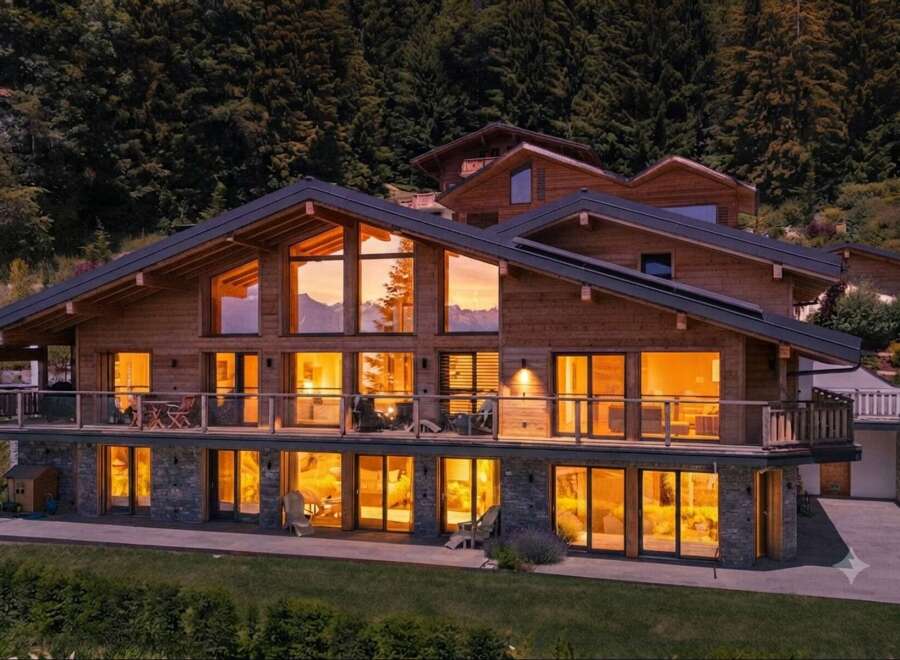 Experience luxury mountain living in this stunning wooden chalet, featuring expansive windows that capture breathtaking sunset views of the surrounding peaks.