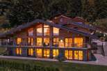 Experience luxury mountain living in this stunning wooden chalet, featuring expansive windows that capture breathtaking sunset views of the surrounding peaks.