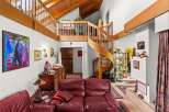 This spacious living area boasts a stunning wooden spiral staircase leading to a lofted area with exposed beams and a vaulted ceiling.