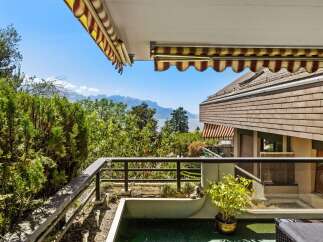 Enjoy breathtaking panoramic views from this stunning balcony, overlooking a serene lake and majestic mountains.