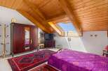 Discover this charming attic bedroom featuring a spacious wooden wardrobe and a vibrant purple quilted bedspread.