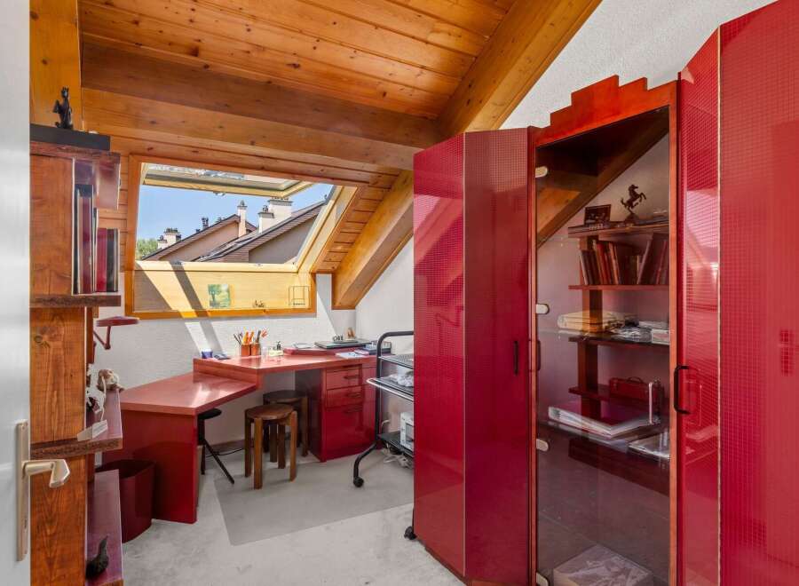 Discover this charming attic workspace, bathed in natural light from a large skylight offering picturesque rooftop views.