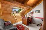 Discover this charming attic room, featuring a cozy black leather sofa and a traditional red oriental rug.