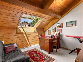 Discover this charming attic room, featuring a cozy black leather sofa and a traditional red oriental rug.