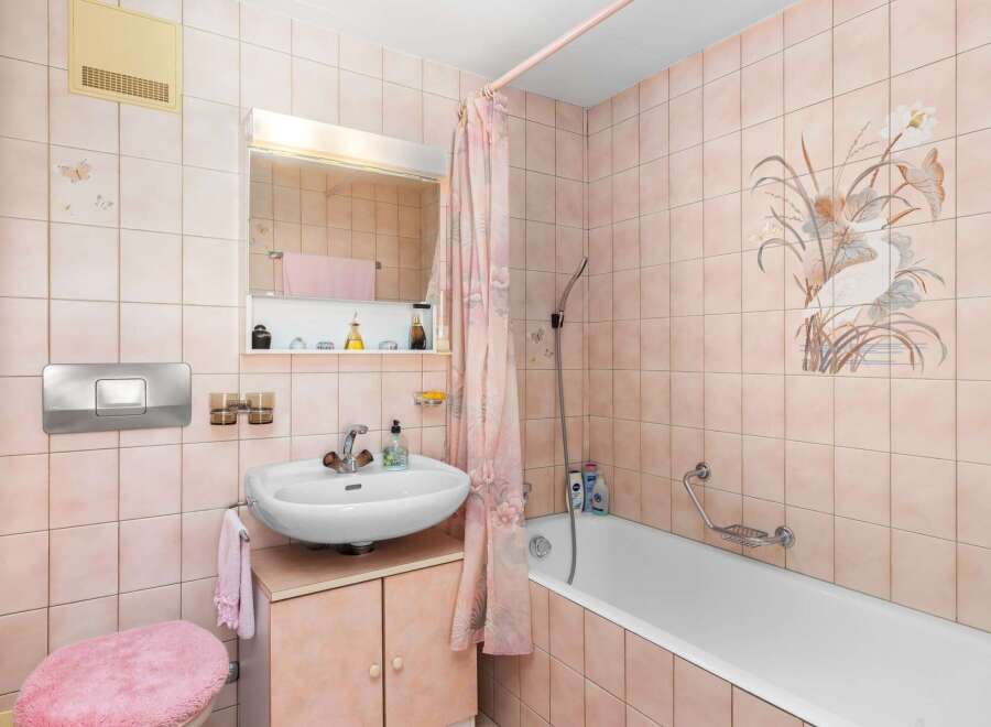 This charming bathroom features a delicate pink tile scheme, creating a warm and inviting atmosphere.