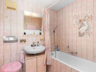 This charming bathroom features a delicate pink tile scheme, creating a warm and inviting atmosphere.