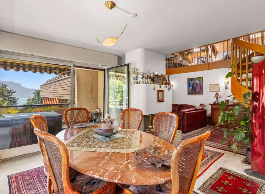 Enjoy breathtaking mountain and lake views from this elegant dining area, featuring a stunning marble-top table surrounded by comfortable wicker chairs.