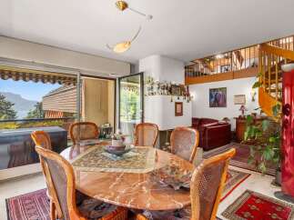 Enjoy breathtaking mountain and lake views from this elegant dining area, featuring a stunning marble-top table surrounded by comfortable wicker chairs.