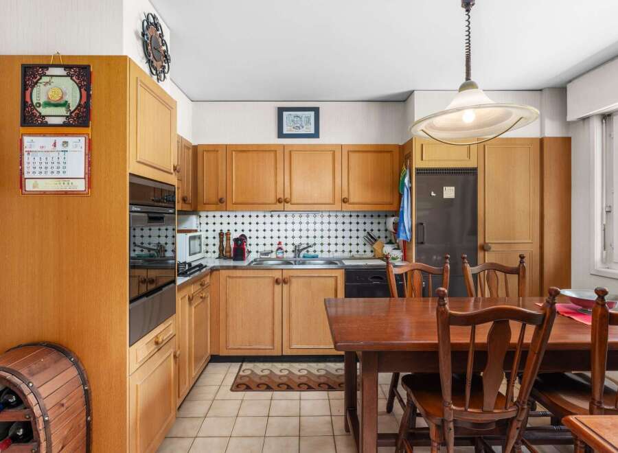 This charming kitchen features warm wooden cabinetry and a classic black and white tiled backsplash, creating a timeless and inviting atmosphere.