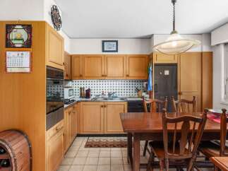 This charming kitchen features warm wooden cabinetry and a classic black and white tiled backsplash, creating a timeless and inviting atmosphere.
