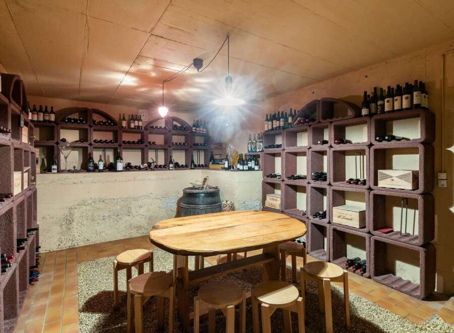 Discover this exceptional wine cellar, featuring a rustic wooden table and stools perfect for tastings.