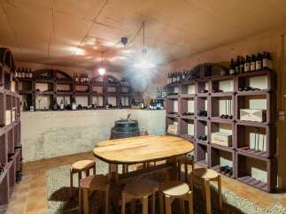 Discover this exceptional wine cellar, featuring a rustic wooden table and stools perfect for tastings.