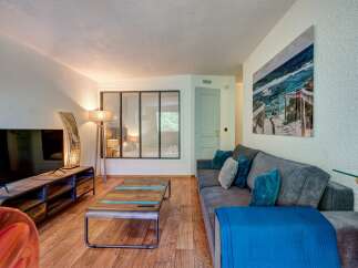 Experience modern living in this stylish living room, featuring a comfortable grey sofa adorned with plush teal and grey cushions, perfect for relaxation.