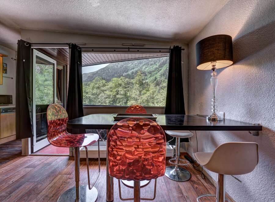 Enjoy breathtaking mountain views from this dining area, featuring a sleek black table and vibrant, modern chairs.
