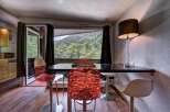 Enjoy breathtaking mountain views from this dining area, featuring a sleek black table and vibrant, modern chairs.