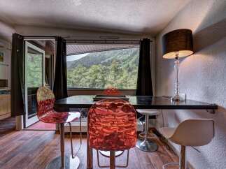 Enjoy breathtaking mountain views from this dining area, featuring a sleek black table and vibrant, modern chairs.