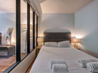 Experience comfort and style in this beautifully appointed bedroom, featuring a plush king-sized bed with crisp white linens and two matching bedside lamps for a warm ambiance.