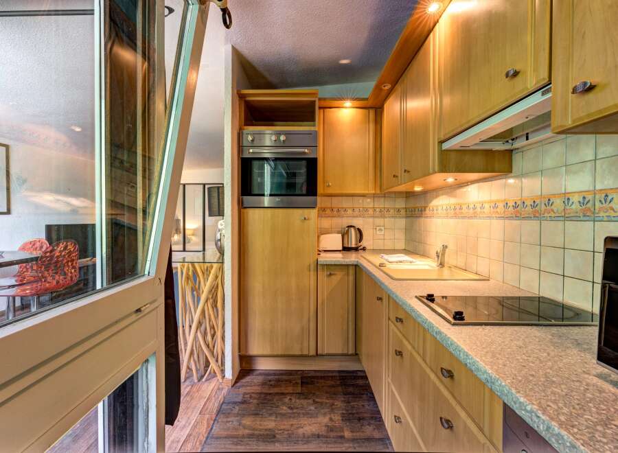 This charming kitchen features light wood cabinetry and a sleek countertop, perfect for meal preparation.