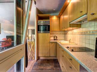 This charming kitchen features light wood cabinetry and a sleek countertop, perfect for meal preparation.