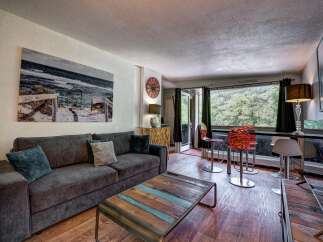 Experience comfortable living in this inviting living room, featuring a plush charcoal sofa adorned with accent pillows and a unique reclaimed wood coffee table.