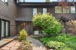 Discover this charming home featuring a welcoming entryway with a stone pathway leading through lush landscaping.