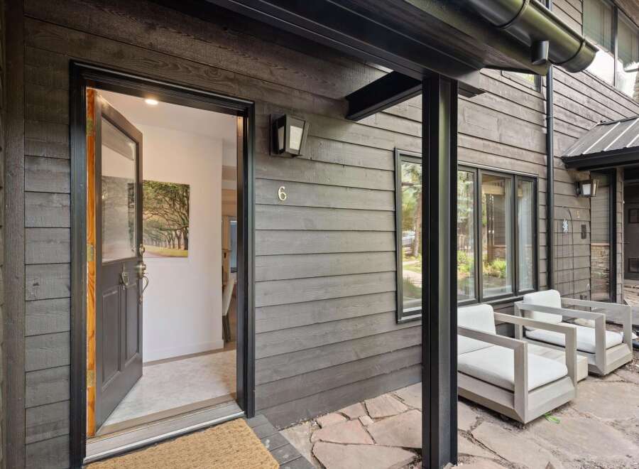 Welcome to this modern mountain home featuring a striking dark wood exterior and a welcoming open doorway.