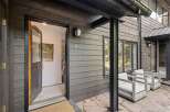 Welcome to this modern mountain home featuring a striking dark wood exterior and a welcoming open doorway.