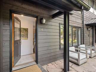 Welcome to this modern mountain home featuring a striking dark wood exterior and a welcoming open doorway.