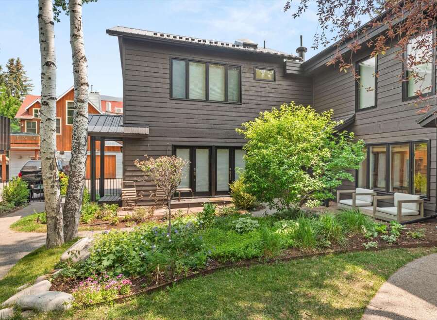 Experience modern living in this stunning home featuring dark wood siding and a sleek metal roof.