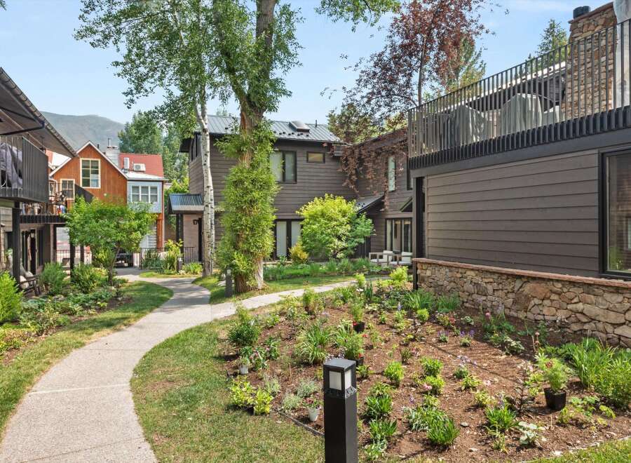 Discover modern living in this beautifully landscaped property, featuring a charming pathway winding through lush gardens.