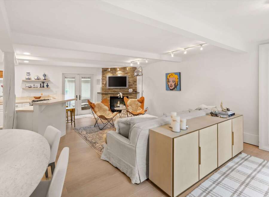 Experience modern living in this open-concept space featuring a stylish kitchen island and a cozy living area centered around a stone fireplace.