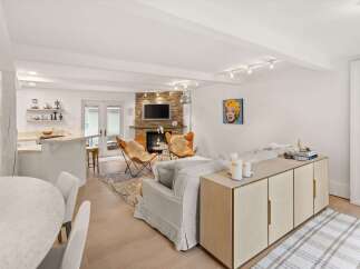 Experience modern living in this open-concept space featuring a stylish kitchen island and a cozy living area centered around a stone fireplace.