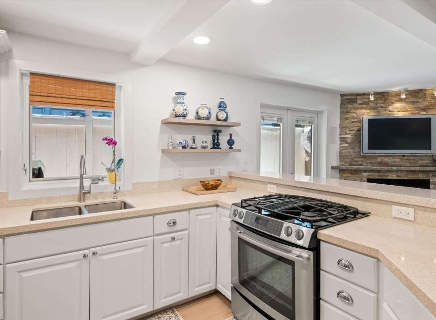 This modern kitchen boasts a sleek stainless steel gas range and a double basin sink, perfect for any home chef.
