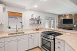 This modern kitchen boasts a sleek stainless steel gas range and a double basin sink, perfect for any home chef.