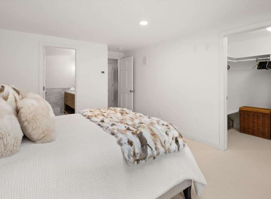 Experience comfort and style in this inviting bedroom, featuring a plush bed adorned with luxurious faux fur pillows and a decorative throw.