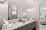This modern bathroom features a spacious double vanity with marble countertops and sleek gray cabinetry.